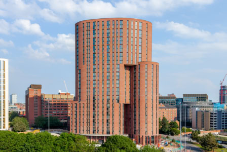Contemporary city skyline featuring a distinctive cylindrical brick building.