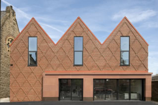 Contemporary brick building with distinctive triangular roof peaks and large windows.