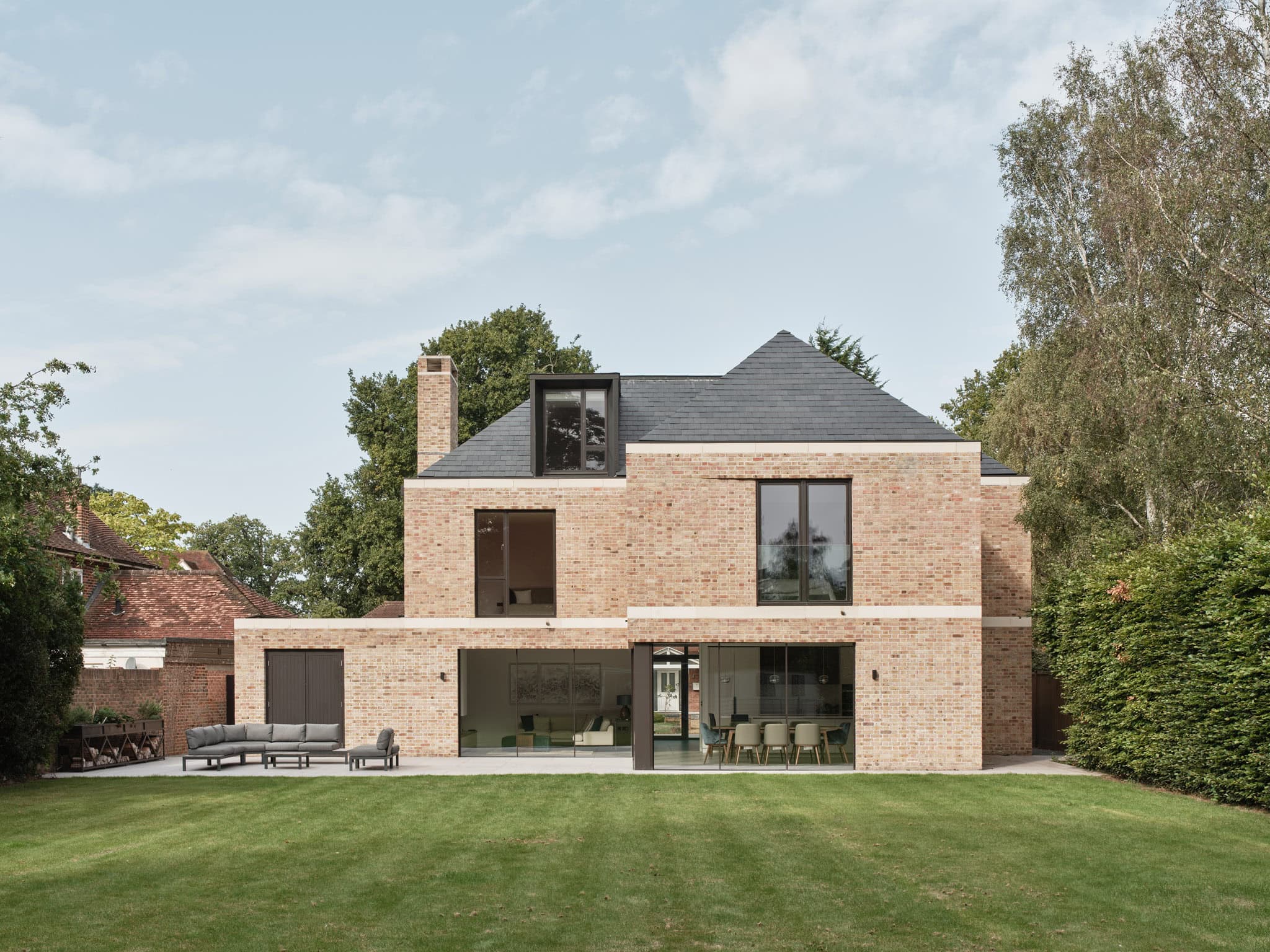 Contemporary brick house with large glass doors and a spacious lawn in Cobham.