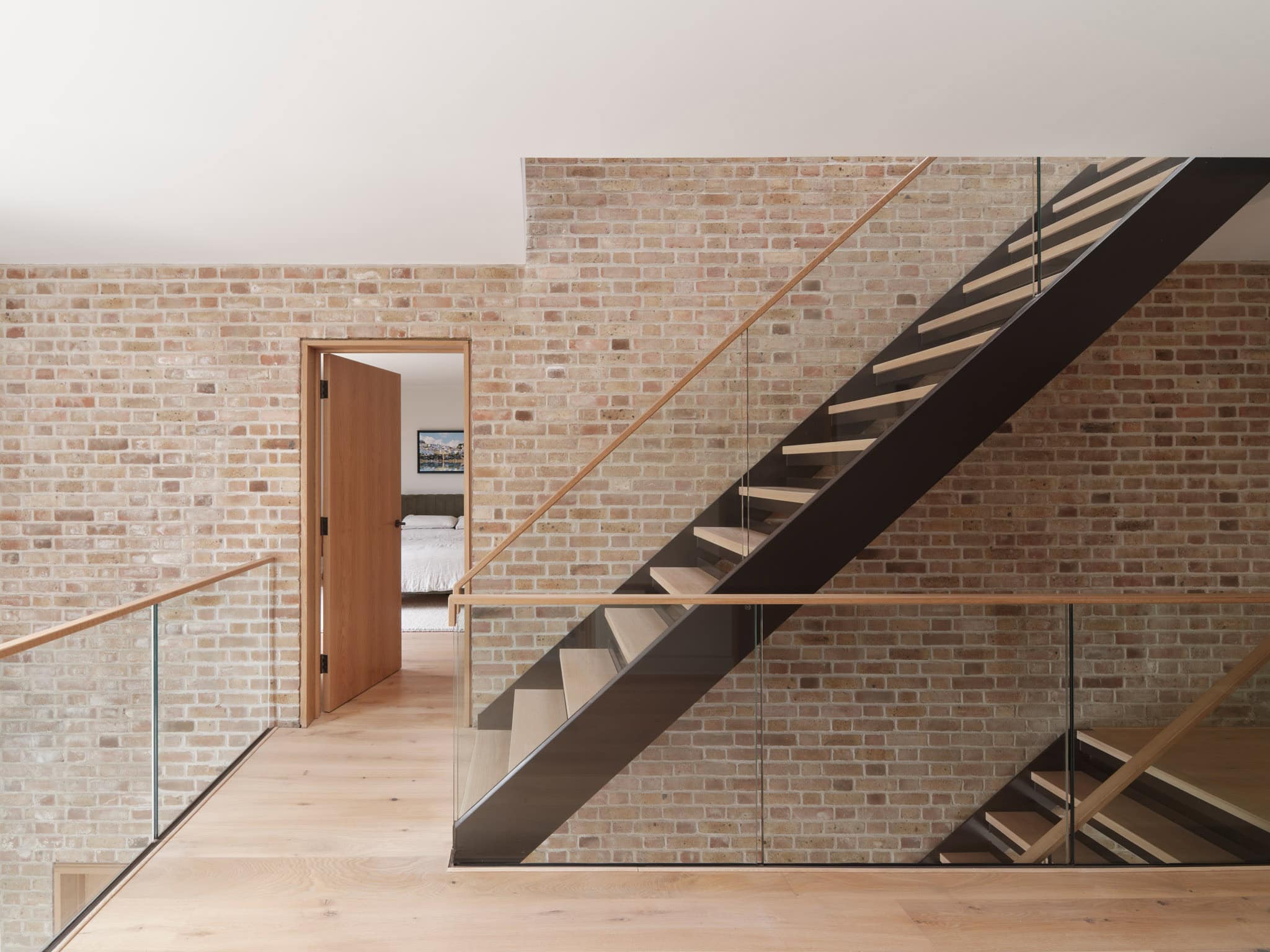 Contemporary staircase with glass balustrades and wooden handrails at Cobham House.