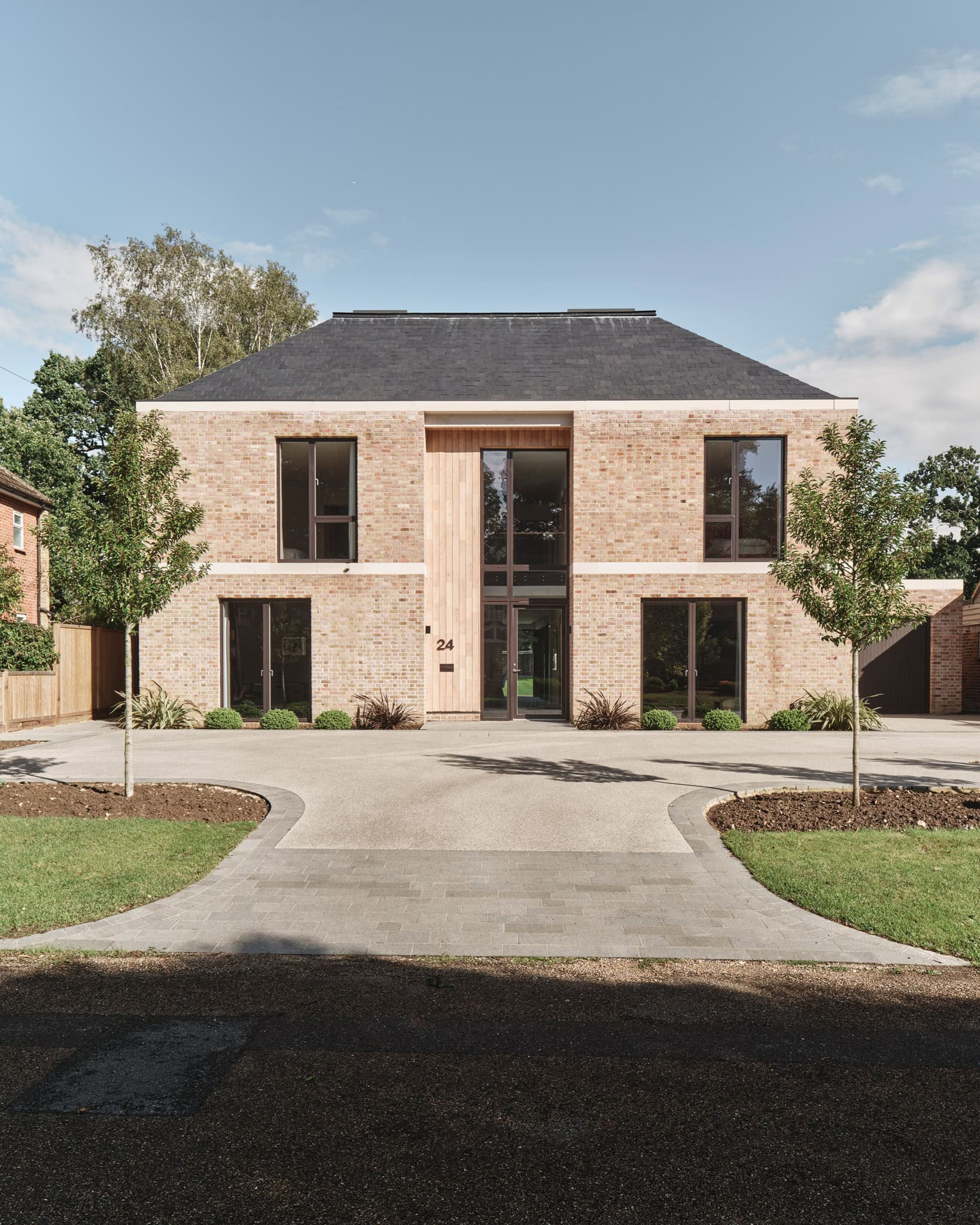 Contemporary brick house with large windows and landscaped front yard.