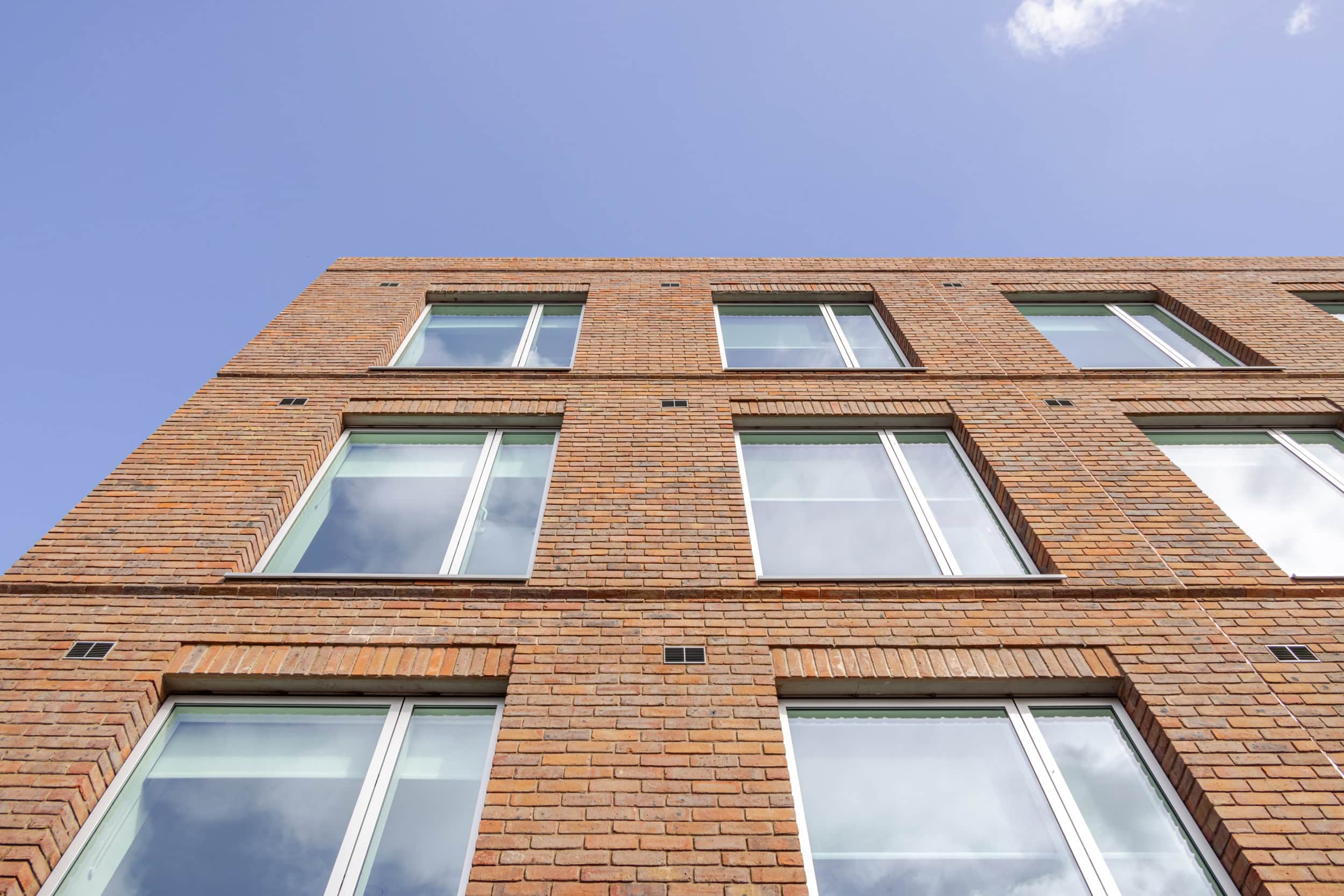 Contemporary brick building with large windows under a blue sky.